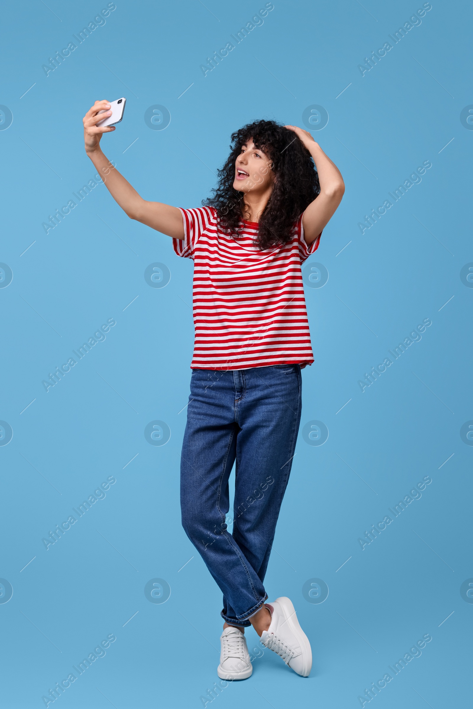 Photo of Beautiful young woman taking selfie on light blue background