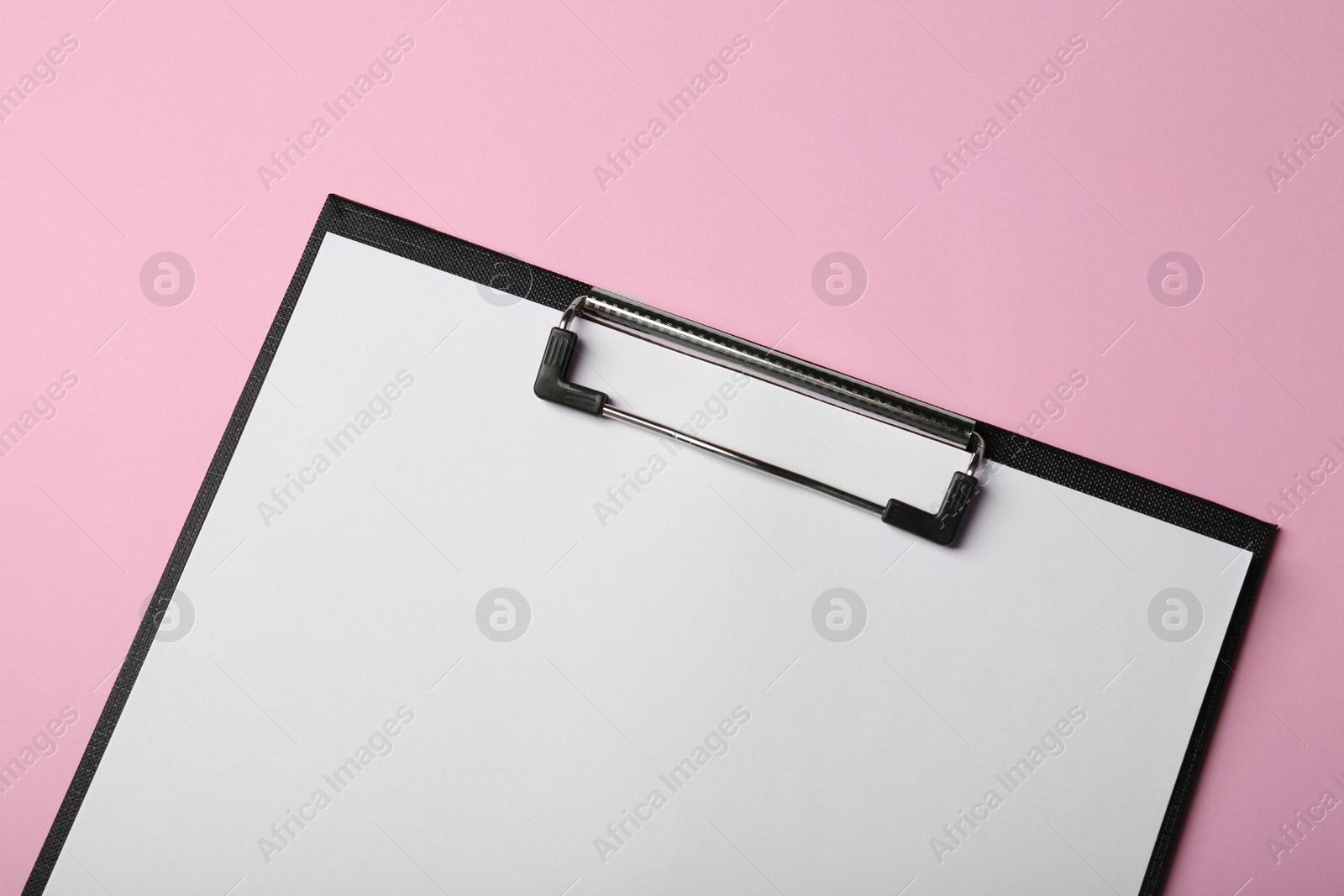 Photo of Black clipboard with sheet of blank paper on pink background, top view