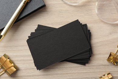 Photo of Blank black business cards and other stationery on wooden table, flat lay. Mockup for design