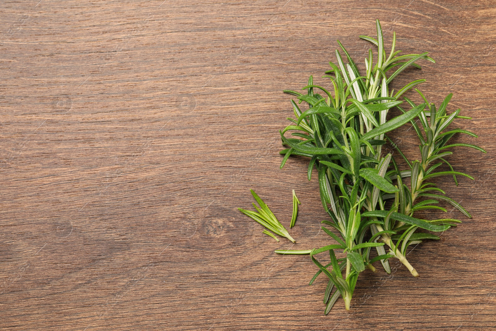 Photo of Fresh green rosemary on wooden table, top view. Space for text