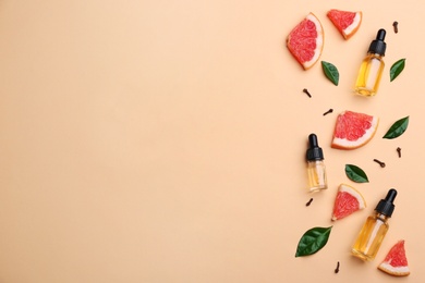 Flat lay composition with grapefruit slices and bottles of essential oil on color background, space for text