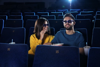 Photo of Young couple with popcorn watching movie in cinema theatre