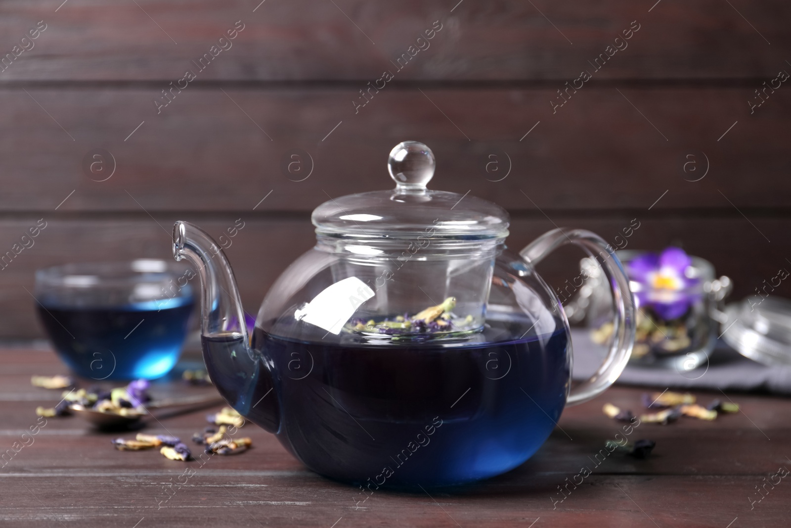 Photo of Organic blue Anchan in teapot on wooden table. Herbal tea