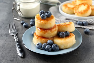 Photo of Delicious cottage cheese pancakes with blueberries and honey on grey table