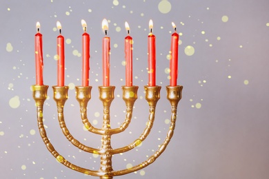 Menorah with burning candles on color background, closeup. Hanukkah celebration