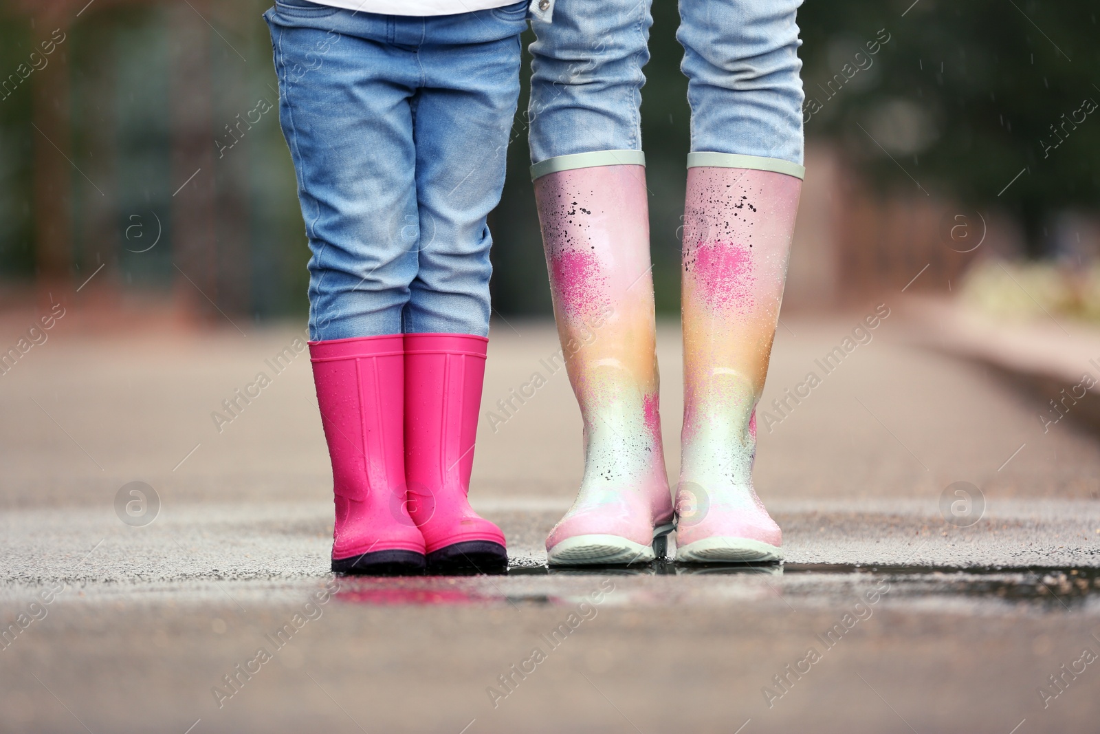 Photo of Mother and daughter wearing rubber boots on street, closeup