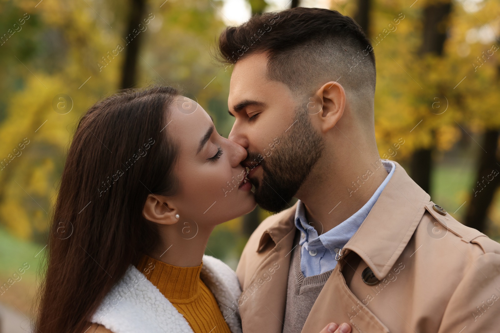 Photo of Happy young couple kissing in autumn park