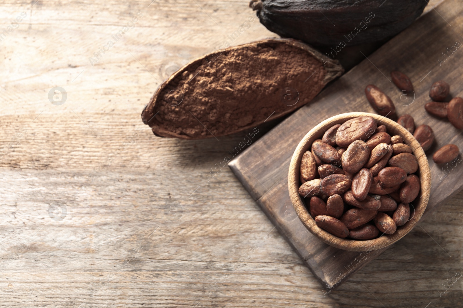 Photo of Flat lay composition with cocoa beans and powder on wooden table, space for text