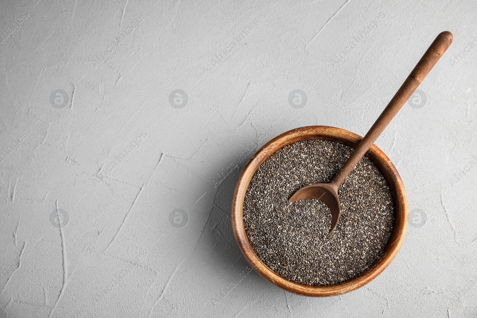 Photo of Bowl and spoon with chia seeds on grey background, top view. Space for text