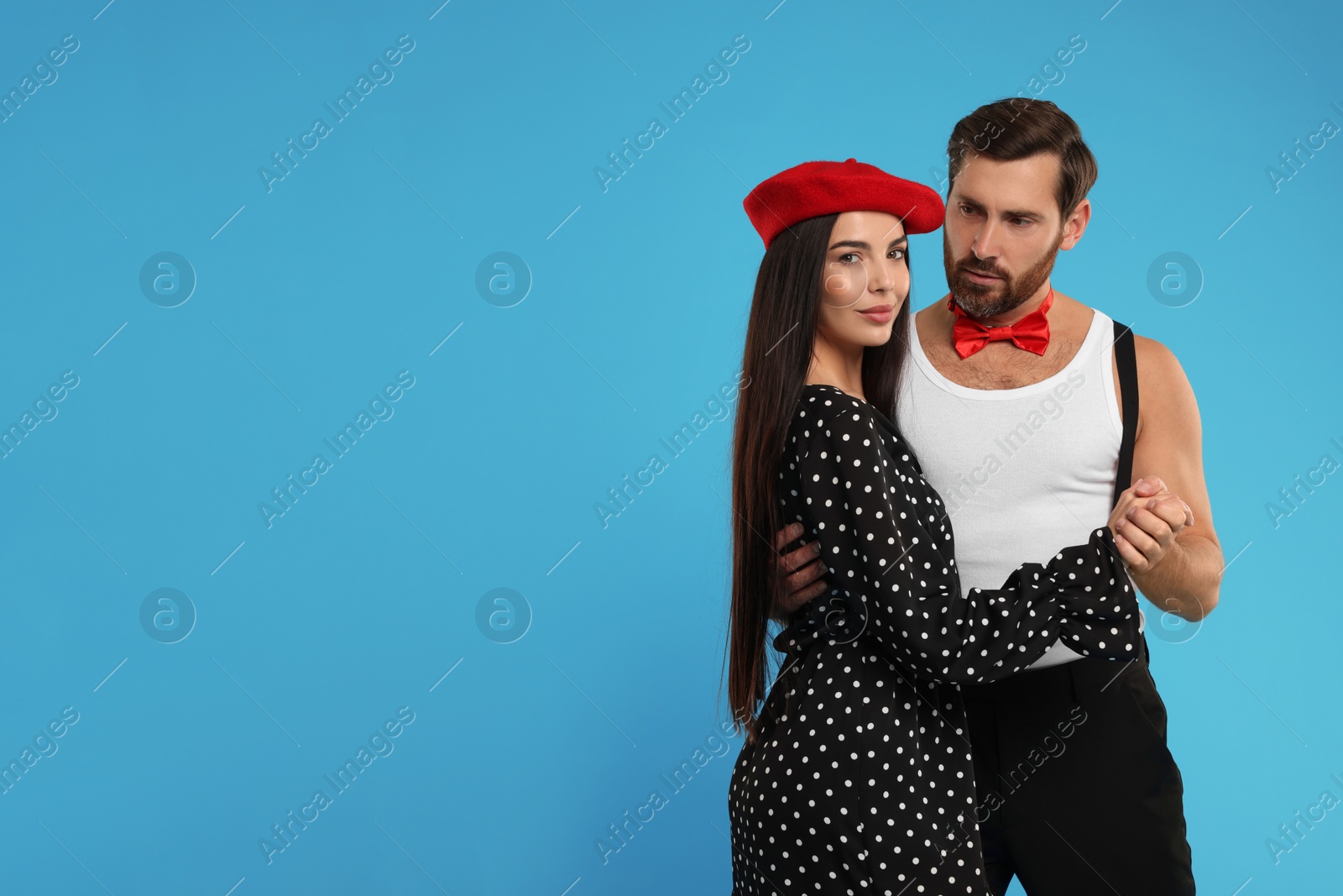 Photo of Beautiful couple dancing together on light blue background, space for text