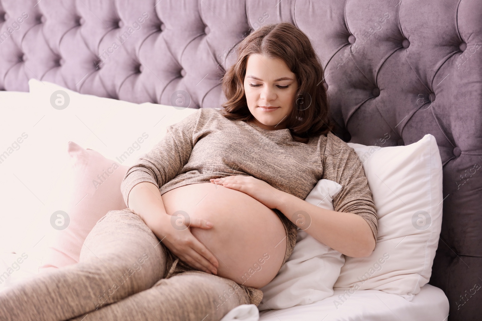 Photo of Young pregnant woman lying on bed at home