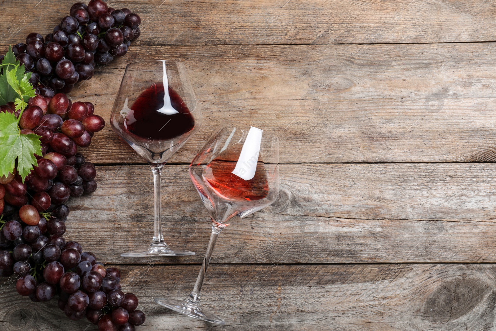 Photo of Flat lay composition with fresh ripe juicy grapes and wine on wooden table, space for text