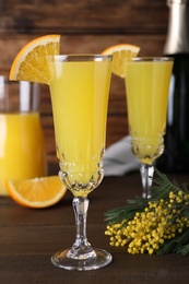 Photo of Glasses of Mimosa cocktail with garnish on wooden table