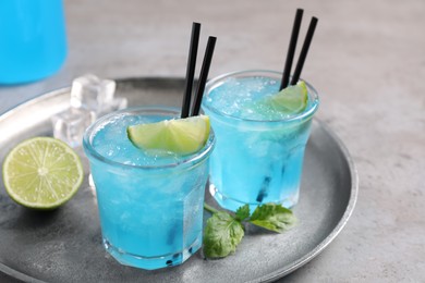 Photo of Tasty fresh light blue drink with lime on grey table