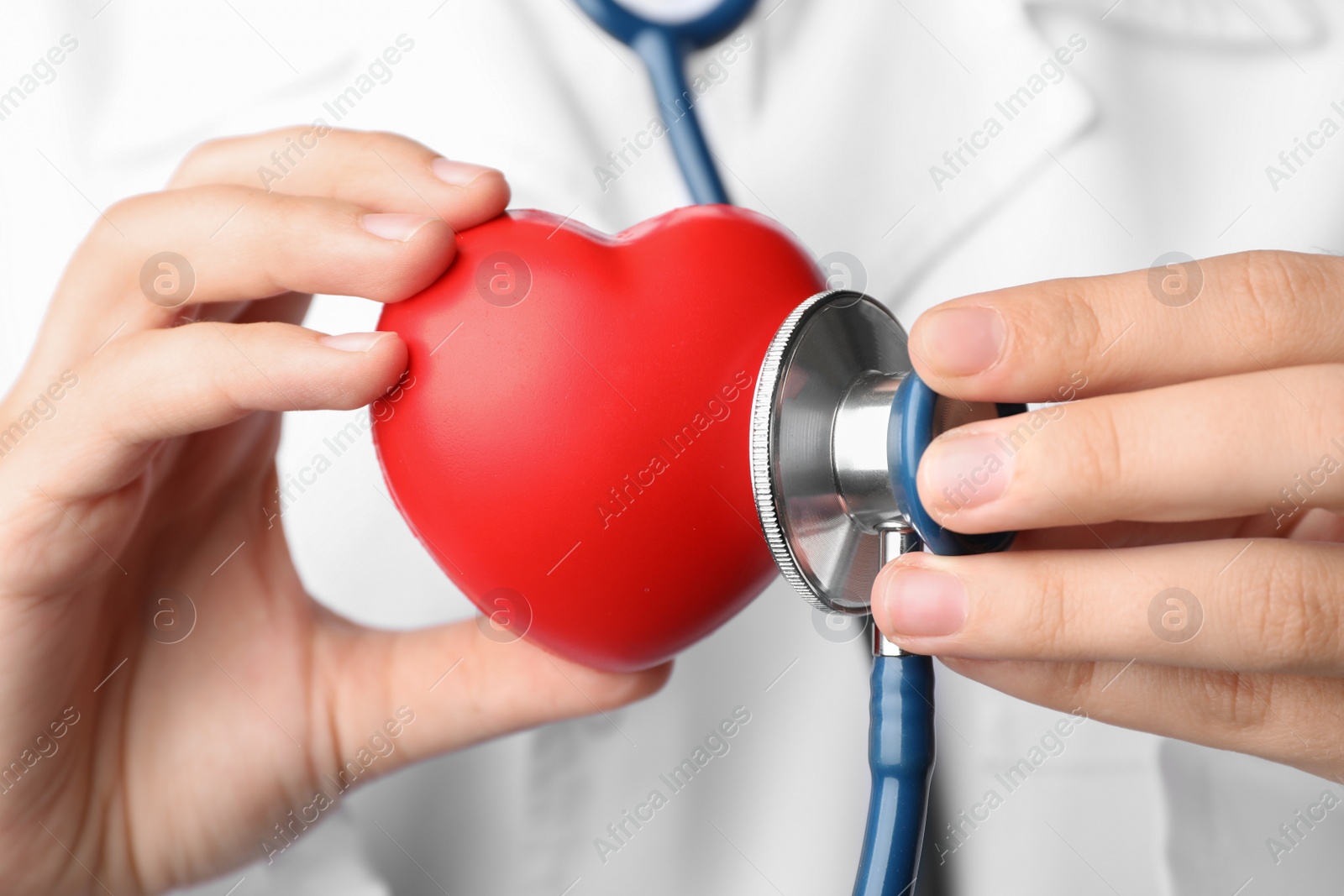 Photo of Doctor holding toy heart and stethoscope, closeup. Pulse checking