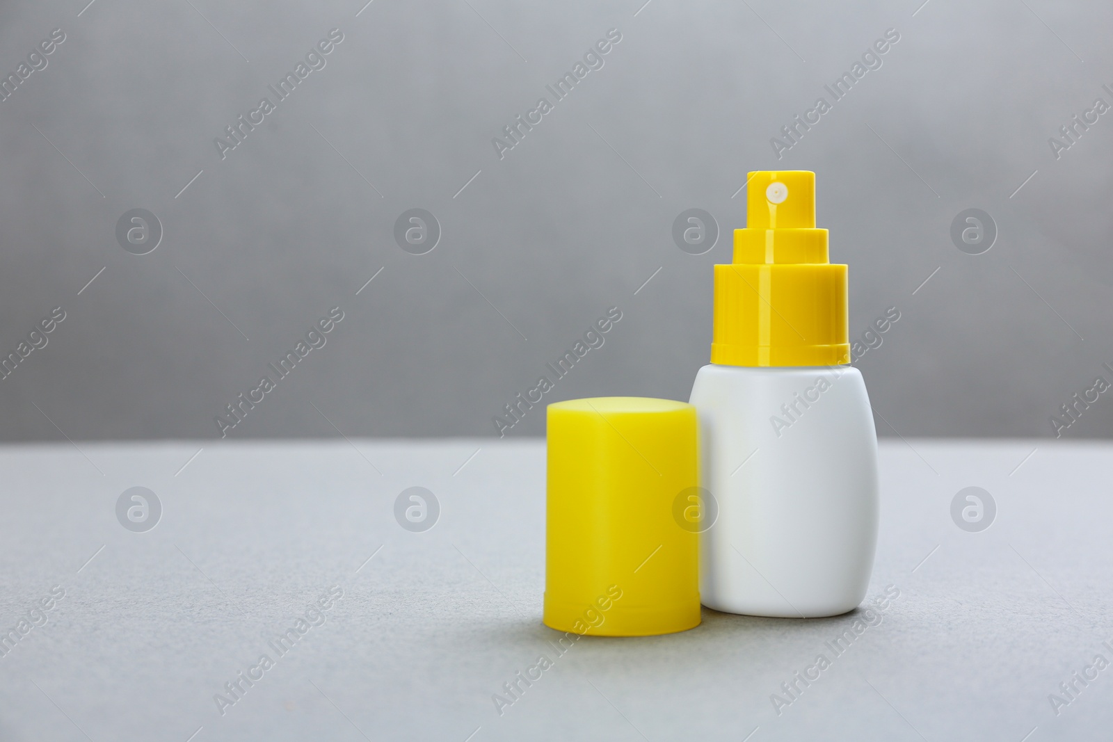 Photo of Bottle with insect repellent spray on grey background, space for text