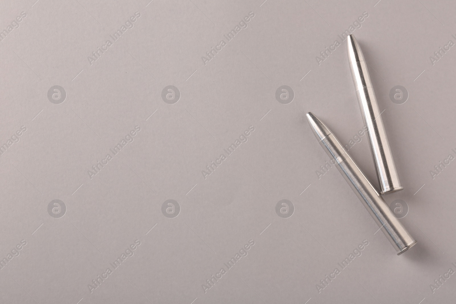 Photo of Two metal bullets on light grey background, flat lay. Space for text