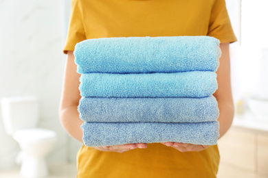 Photo of Woman holding fresh towels in bathroom, closeup