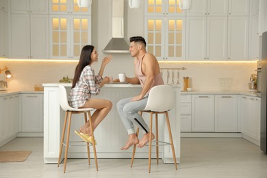 Happy couple wearing pyjamas during breakfast at table in kitchen