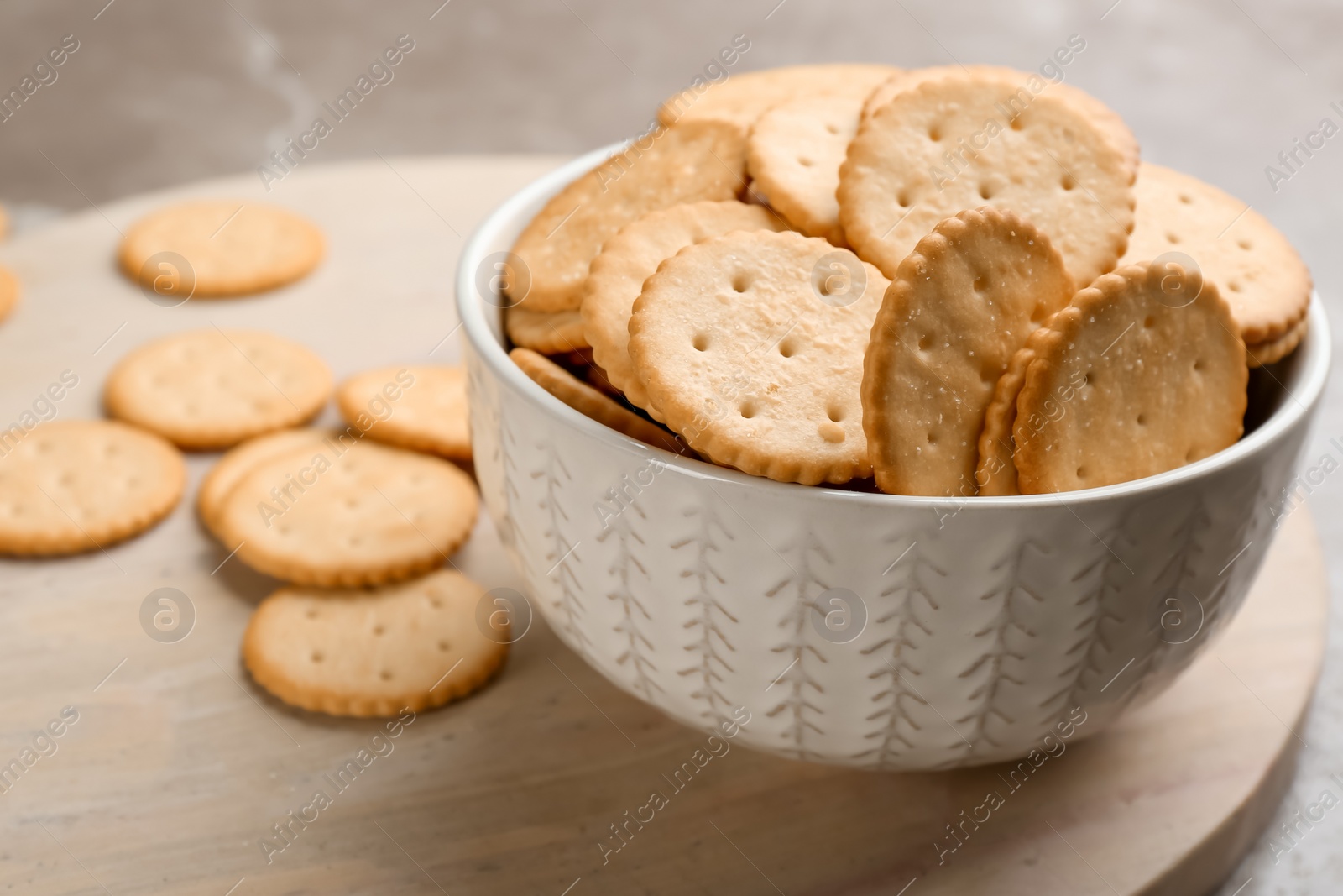 Photo of Delicious crispy crackers on wooden board, closeup