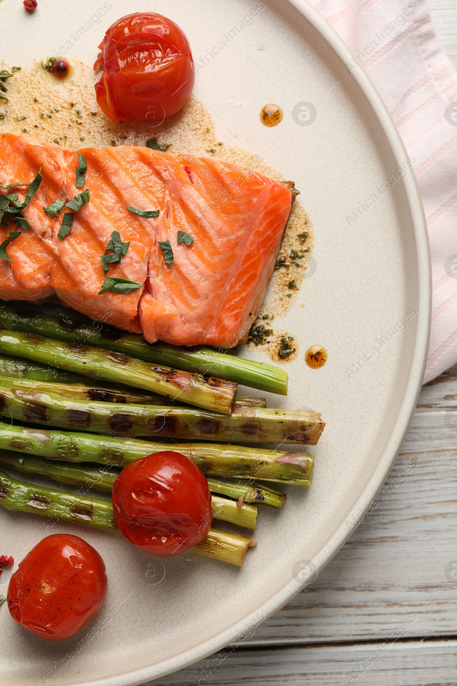 Photo of Tasty grilled salmon with tomatoes, asparagus and spices on plate, top view