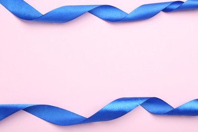 Beautiful blue ribbons on pink background, flat lay. Space for text