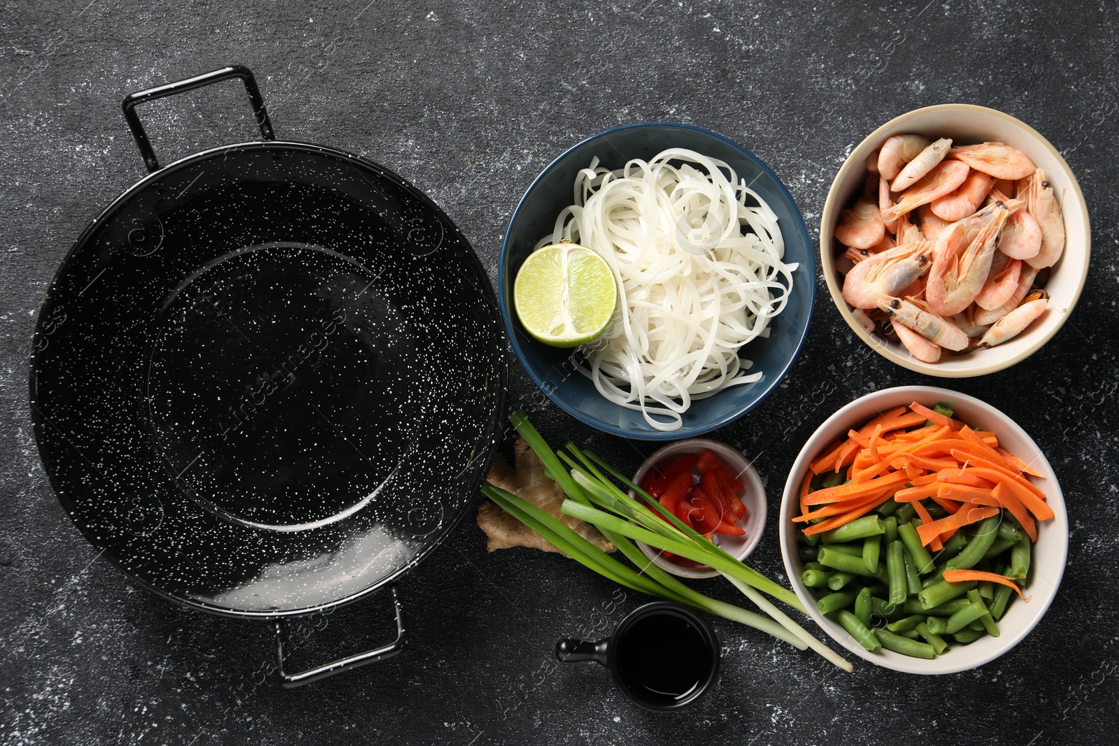 Photo of Flat lay composition with black wok and products on dark textured table