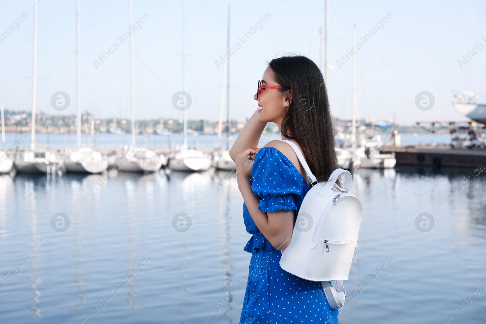 Photo of Beautiful young woman with stylish backpack near river