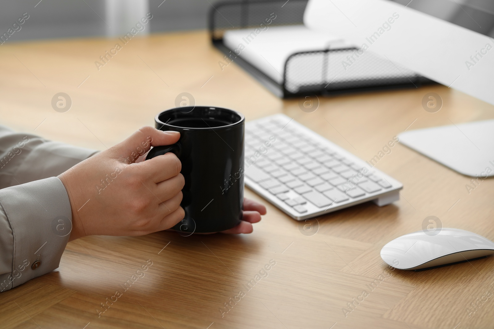 Photo of Woman with black ceramic mug at workplace, closeup