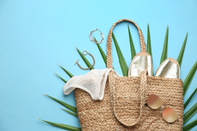 Flat lay composition with woman's straw bag on light blue background