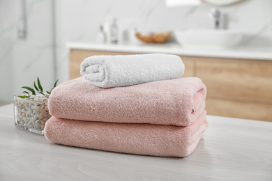 Photo of Fresh towels and salt on white table in bathroom