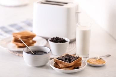 Photo of Modern toaster and delicious breakfast on table in kitchen