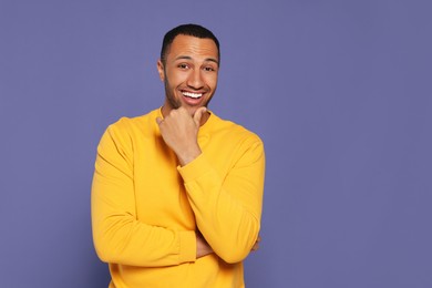 Photo of Portrait of happy African American man on purple background. Space for text