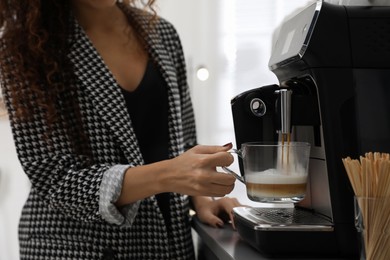 Photo of African American woman preparing fresh aromatic coffee with modern machine in office, closeup