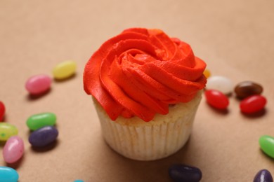 Photo of Delicious cupcakes with bright cream and candies on brown background, closeup