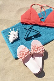 Photo of Towel, flip flops and bra on sand, above view. Beach accessories