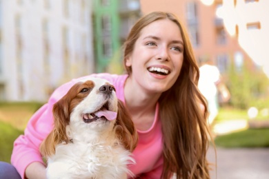 Photo of Young woman with adorable Cavalier King Charles Spaniel dog outdoors