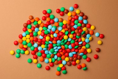 Photo of Tasty colorful candies on light brown background, flat lay