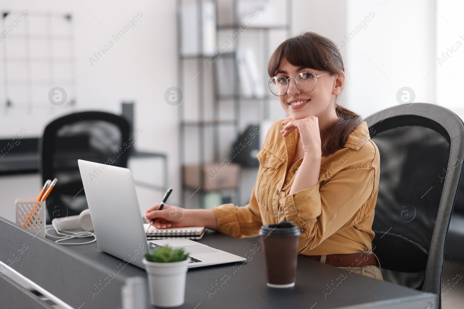 Photo of Woman taking notes during webinar at table indoors