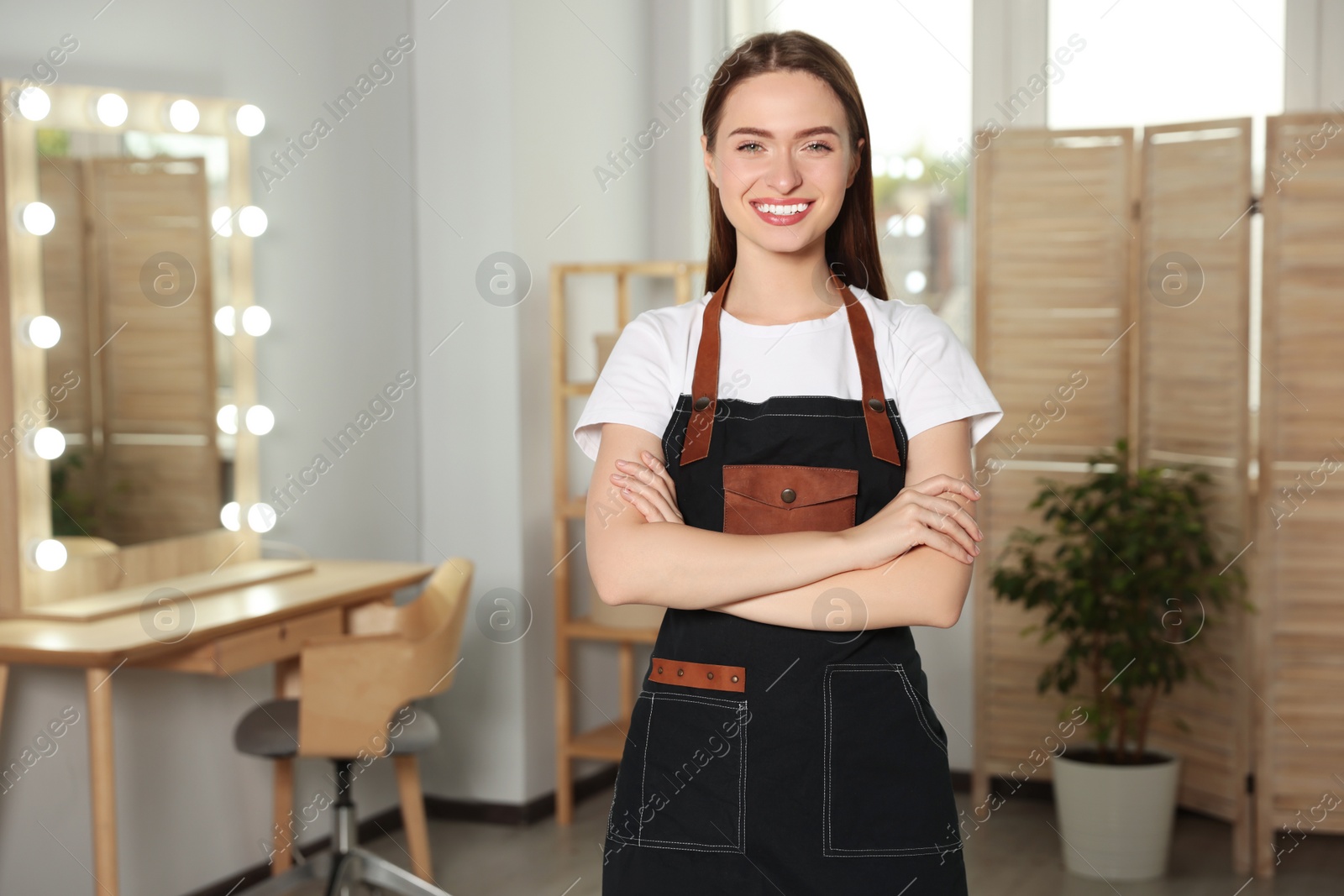 Photo of Portrait of professional hairdresser wearing apron in beauty salon