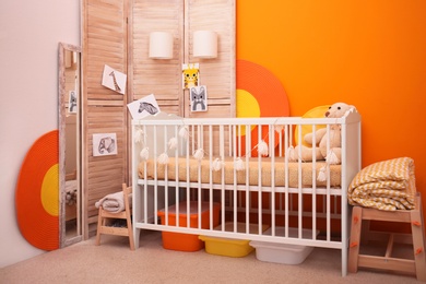 Photo of Baby room interior with crib near color wall