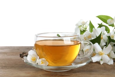 Photo of Glass cup of aromatic jasmine tea and fresh flowers on wooden table against white background