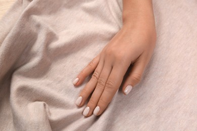 Photo of Woman touching soft beige fabric, closeup view