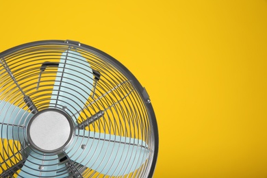 Photo of Modern electric fan on yellow background, closeup. Space for text
