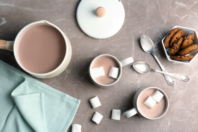 Flat lay composition with hot cocoa drink, marshmallows and cookies on grey table