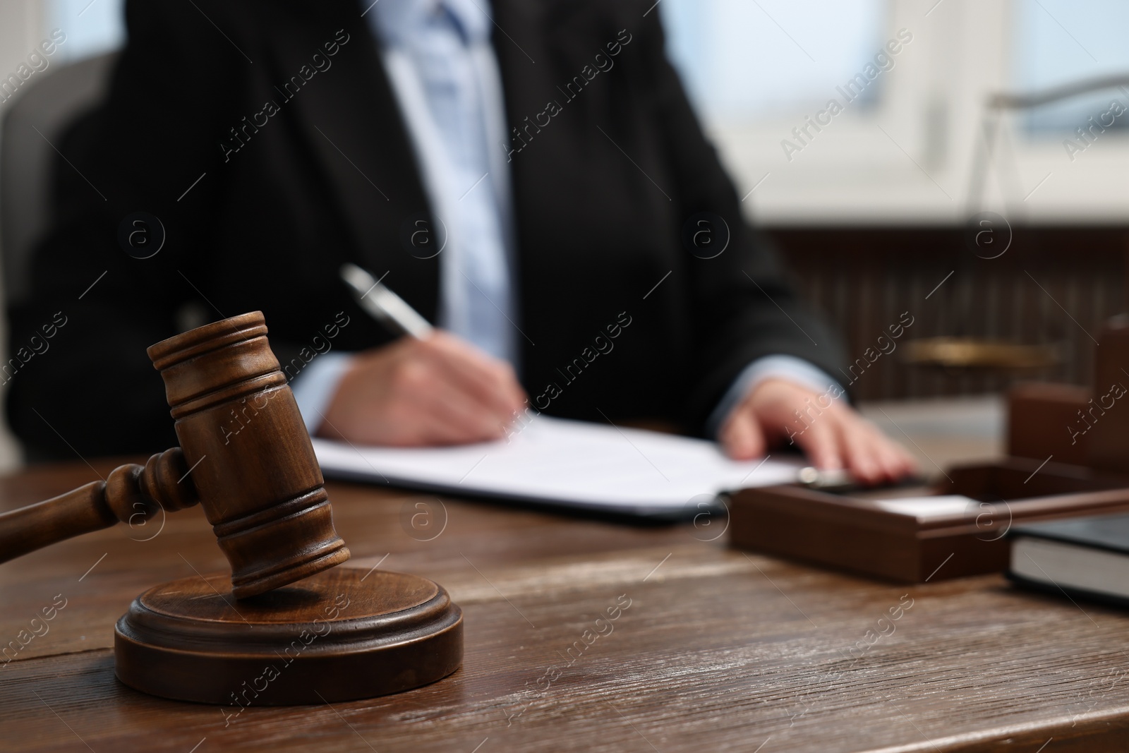 Photo of Lawyer working at wooden table in office, focus on gavel