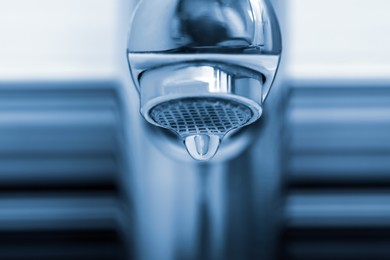 Image of Water drop falling down from tap on blurred background, closeup