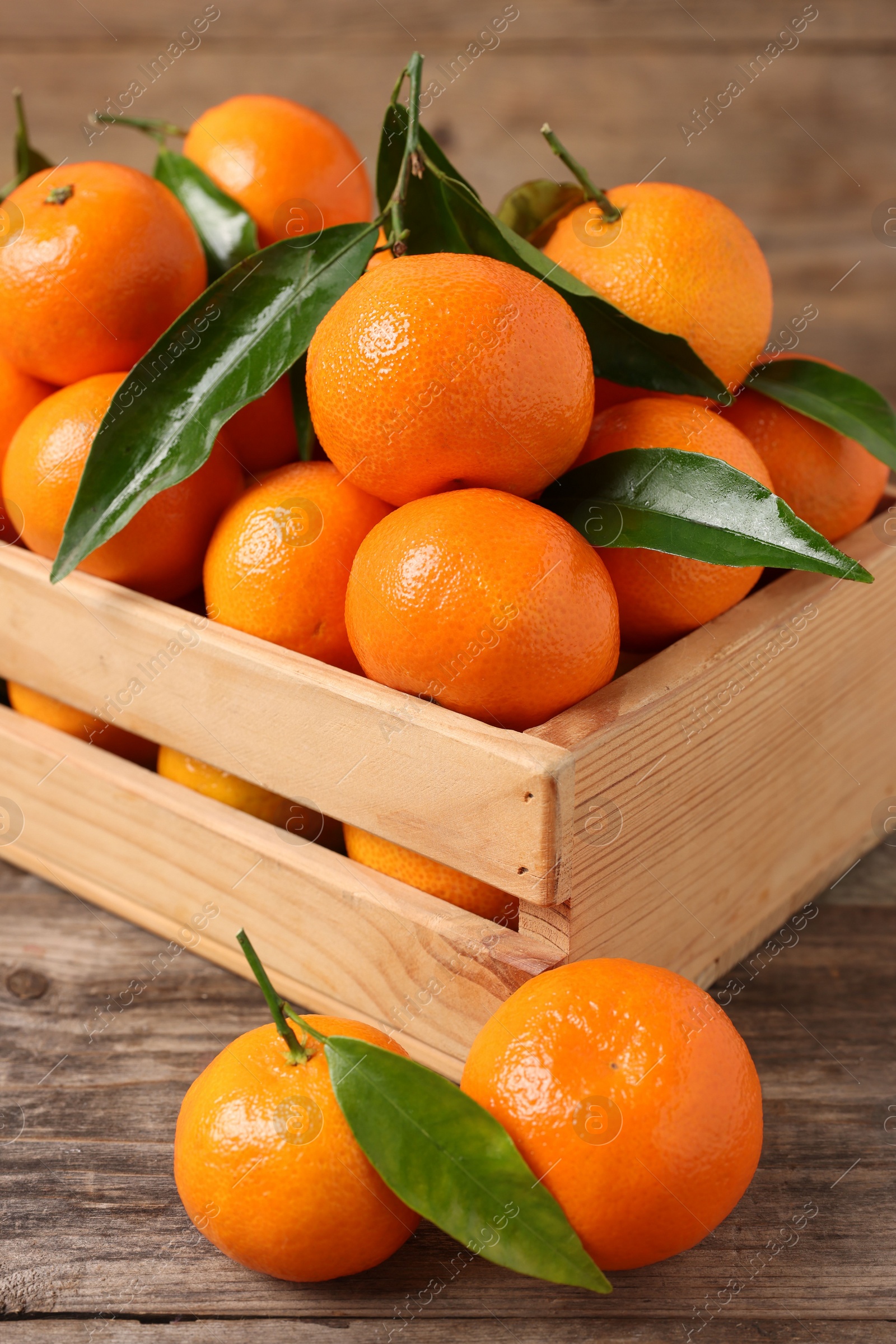 Photo of Delicious tangerines with leaves on wooden table