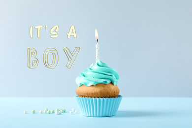 Image of Baby shower cupcake with candle for boy on light blue table