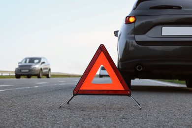 Photo of Emergency warning triangle near car on roadside. Tire puncture